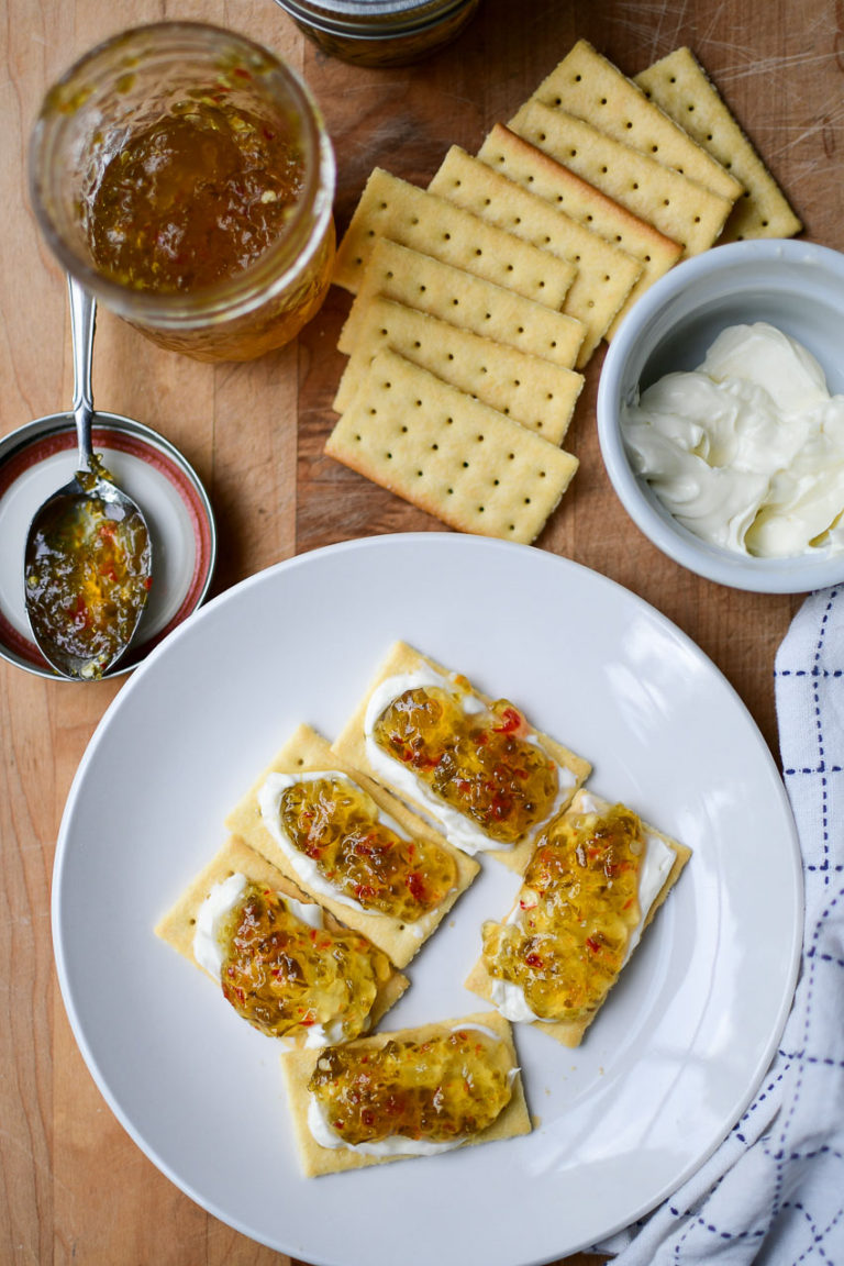 A plate of club crackers topped with cream cheese and pepper jelly