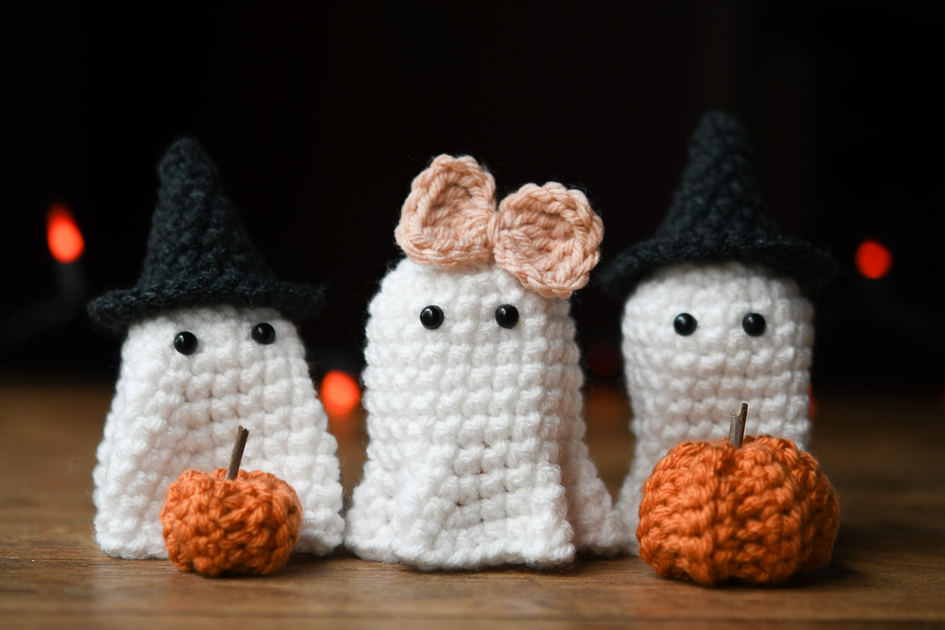 Trio of crocheted ghosts with mini pumpkins, witch hats and a bow. 