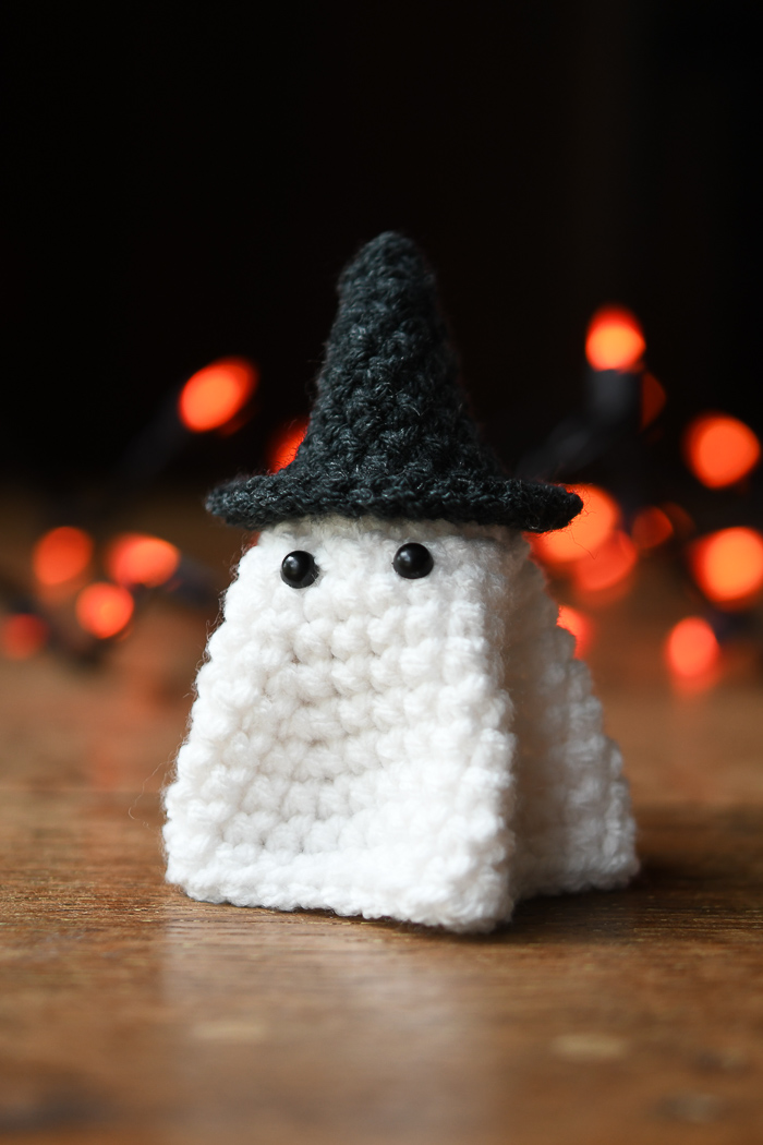 A short crochet ghost wearing a witch hat