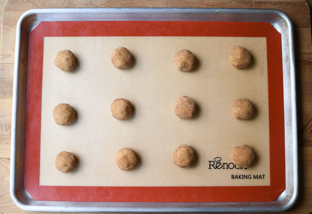 A baking tray with 12 dough balls of brown butter snickerdoodles ready to bake. 