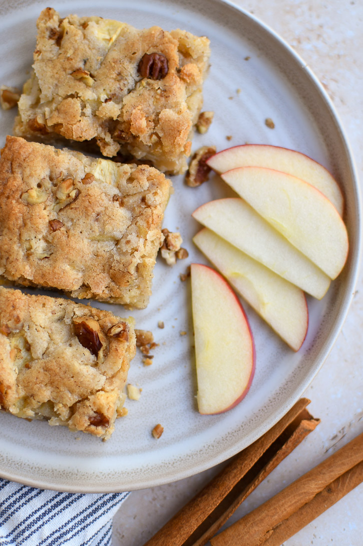 Apple Brownies on a plate with slices of Honey Crisp Apple and cinnamon sticks