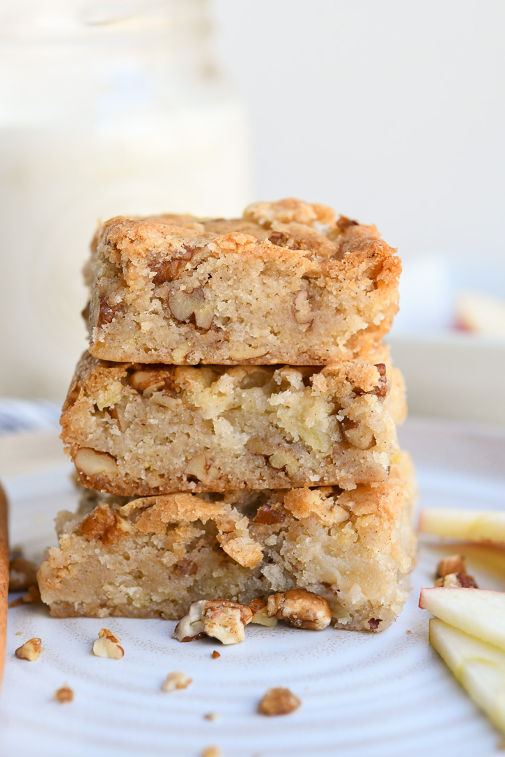 3 Apple Brownies stacked on a plate with candied pecan pieces