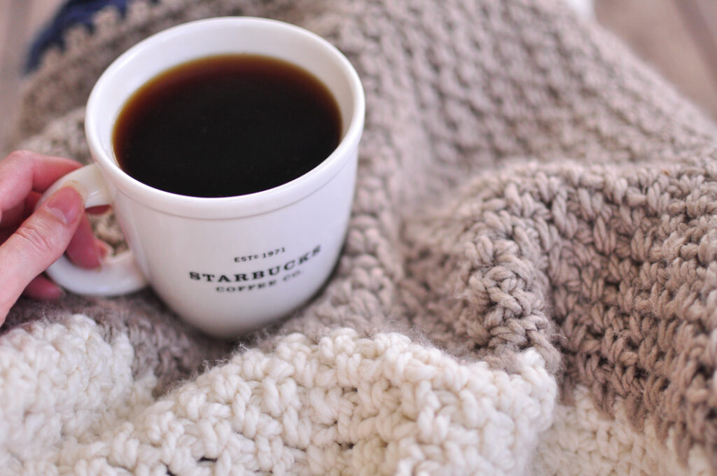 A blanket crocheted with the moss stitch and a cup of black coffee