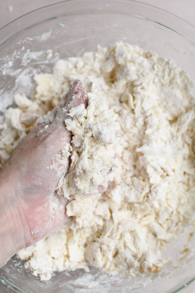 Gently squeezing the mixture together to begin to form a shortbread dough