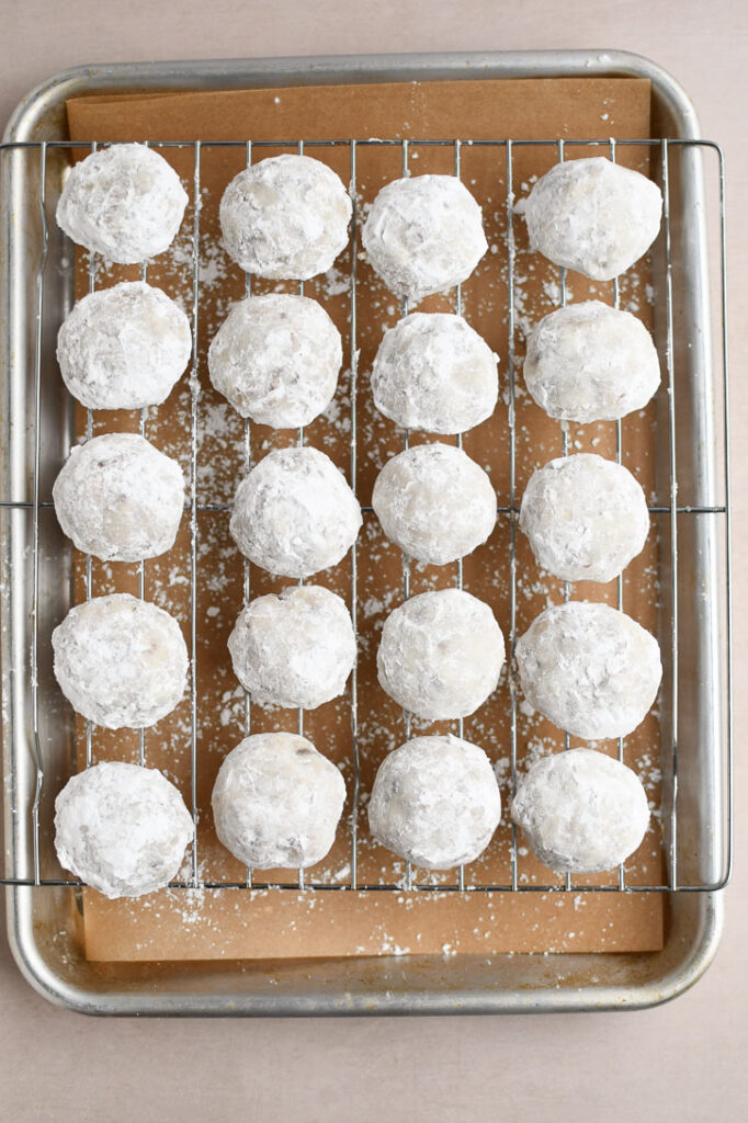 Snowball cookies on a wire rack after the second rolling in powdered sugar 