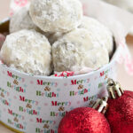 A stack of Snowball Cookies in a Christmas tin