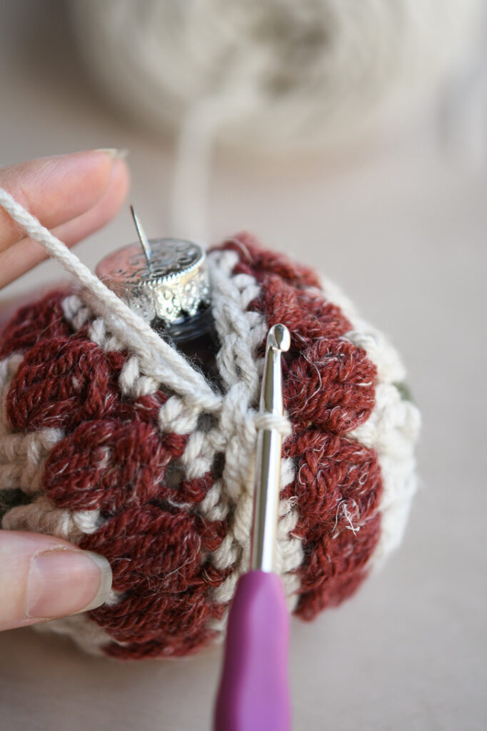 A close up continuing to slip stitch the edges with the plastic ornament inside