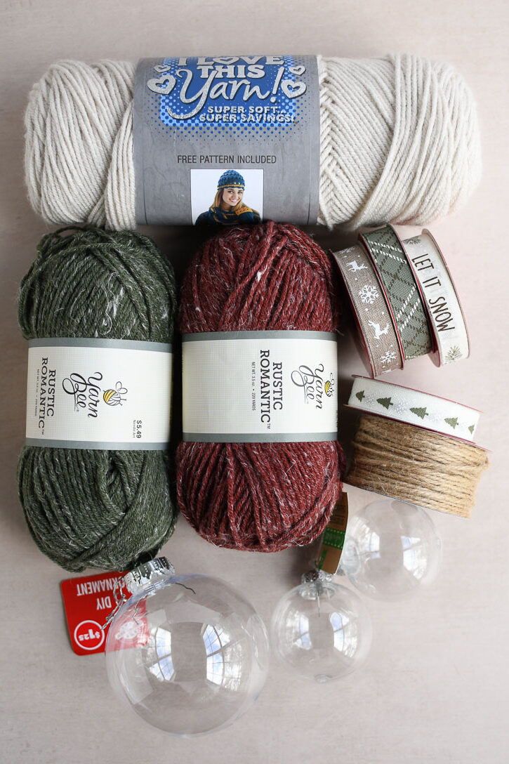 The supplies needed to make crochet ornaments-yarn, ribbon, twine, and plastic ornament inserts.