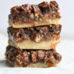 A stack of three chocolate pecan pie bars showing the inside layers