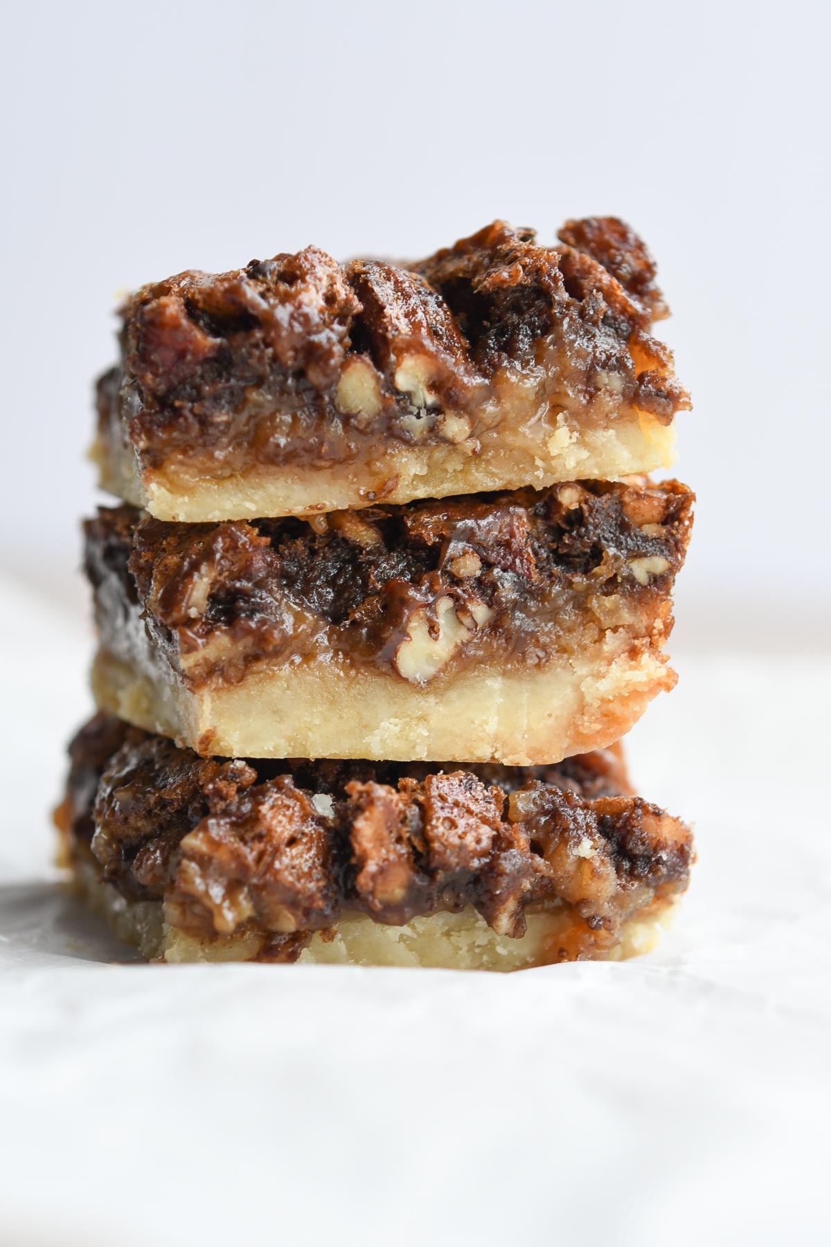 A stack of three chocolate pecan pie bars showing the inside layers