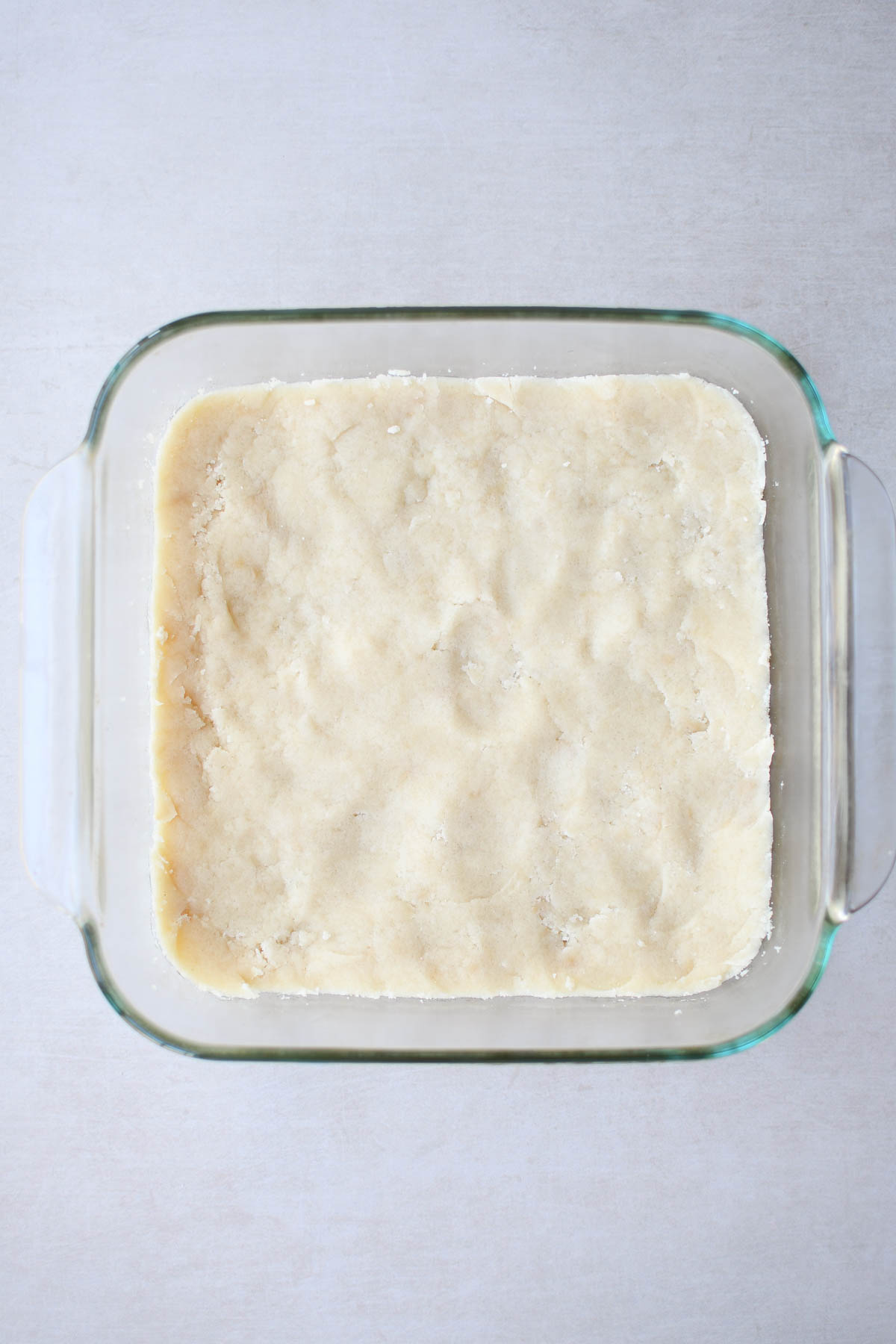 Shortbread dough pressed into a pan to make the crust for the pecan pie bars