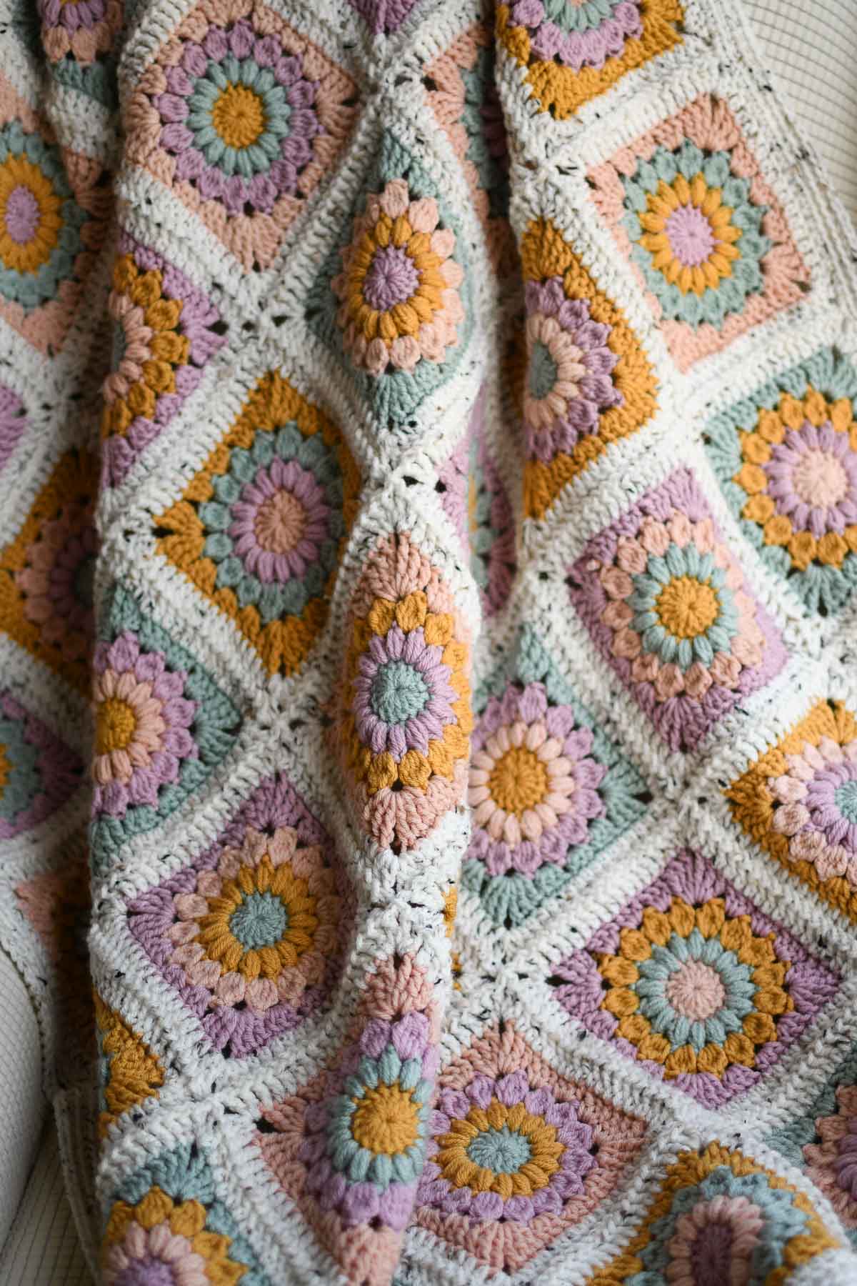 An image of a crochet sunburst blanket draped across a chair