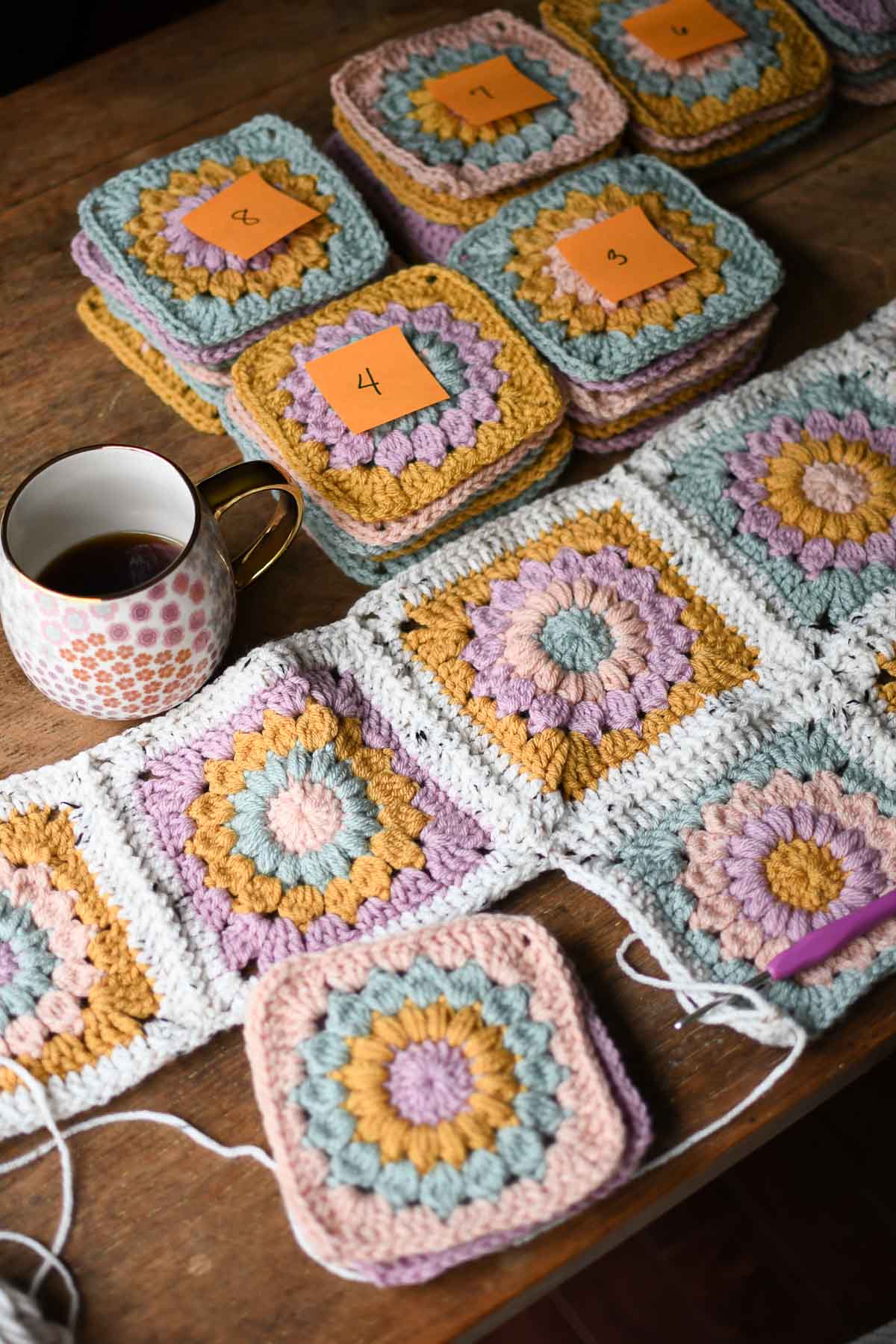 An in process shot showing stacks of granny squares and squares being joined to the blanket