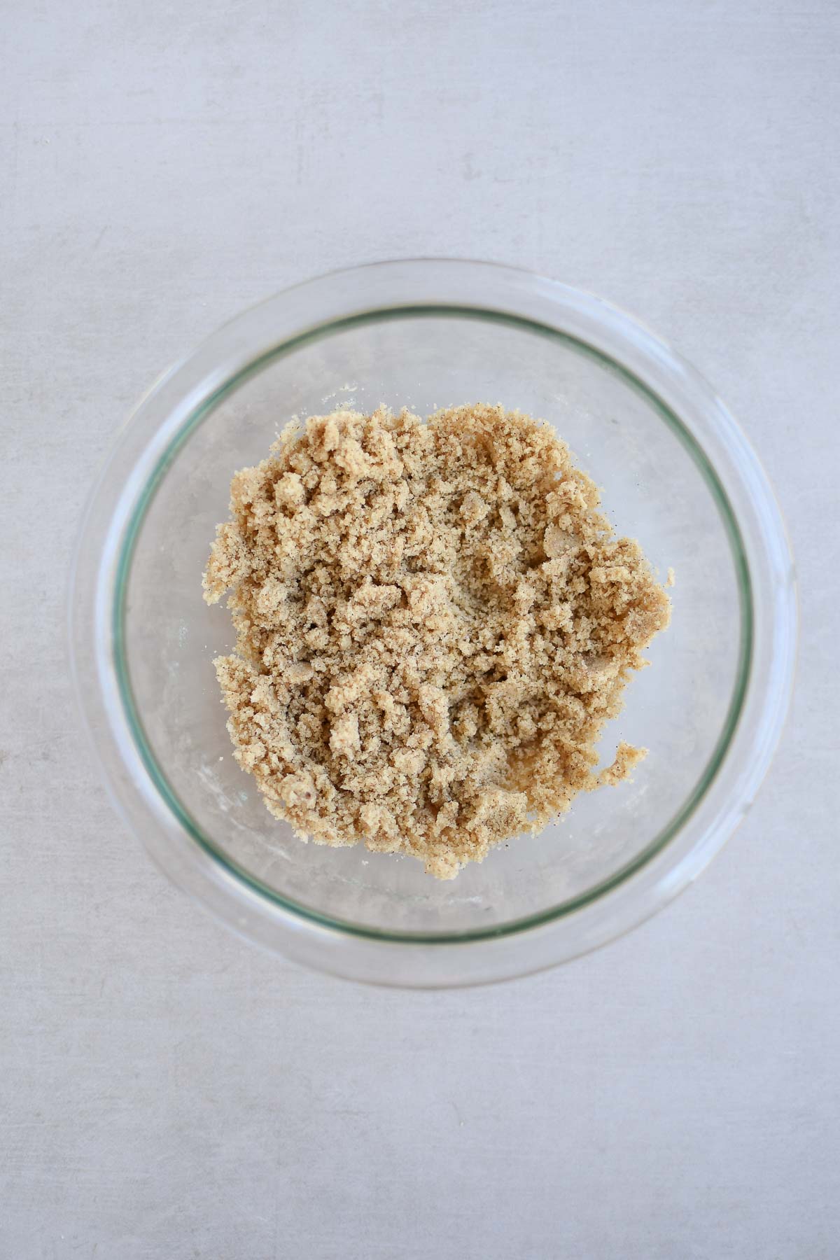 A bowl with a sandy mixture of streusel topping